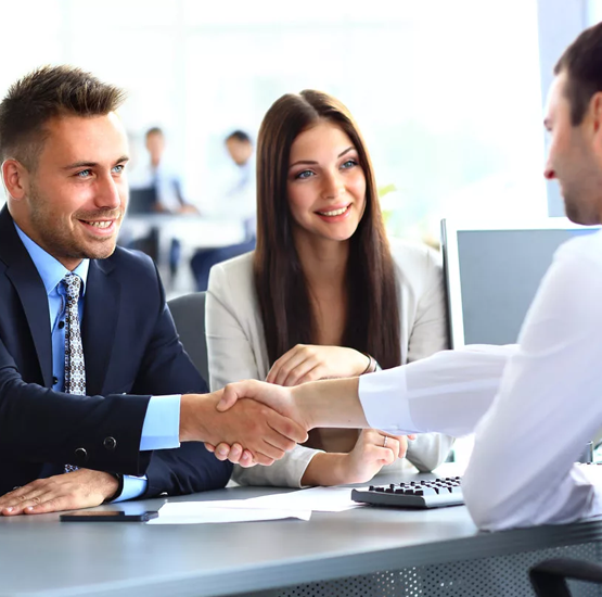 A man shaking hands with another person in front of two other people.