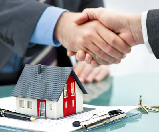Two people shaking hands over a house.